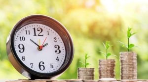 Money is not scare - Picture showing stacks of coins (money) with plants growing and a clock, portraying wealth is built